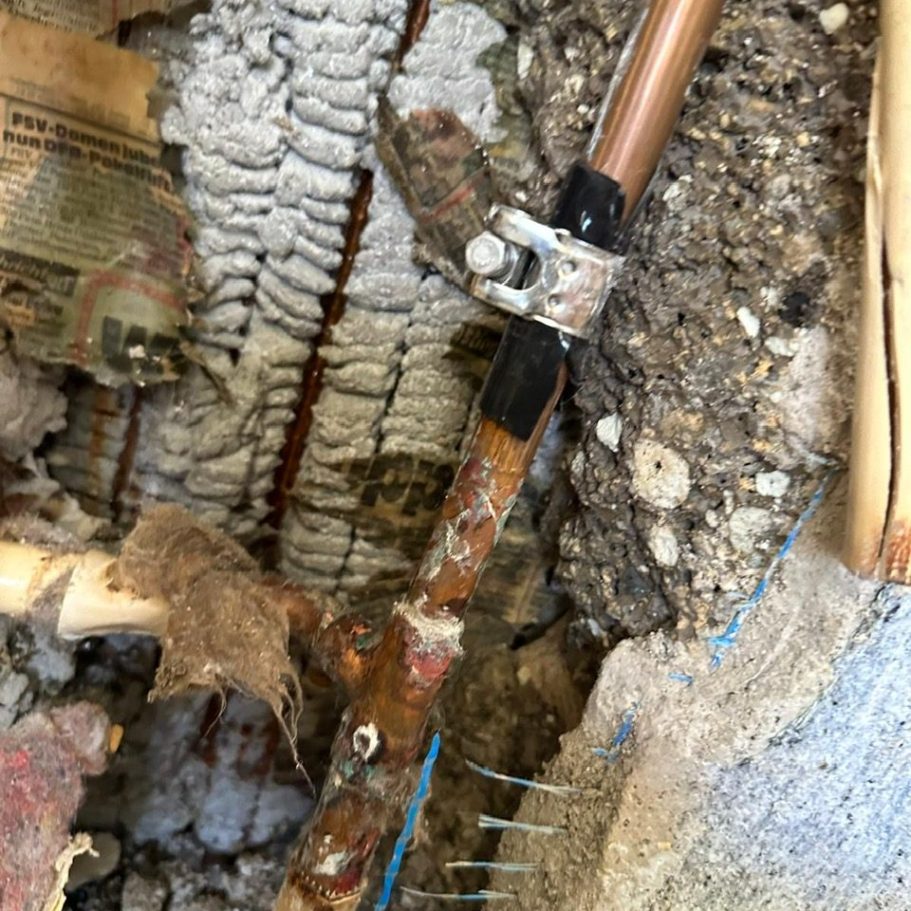 Rohrbruchreparatur und Notabdichtung – Rohrbruchexpress Wetterau Freigelegte Kupferleitung mit Schelle an der Schadenstelle.